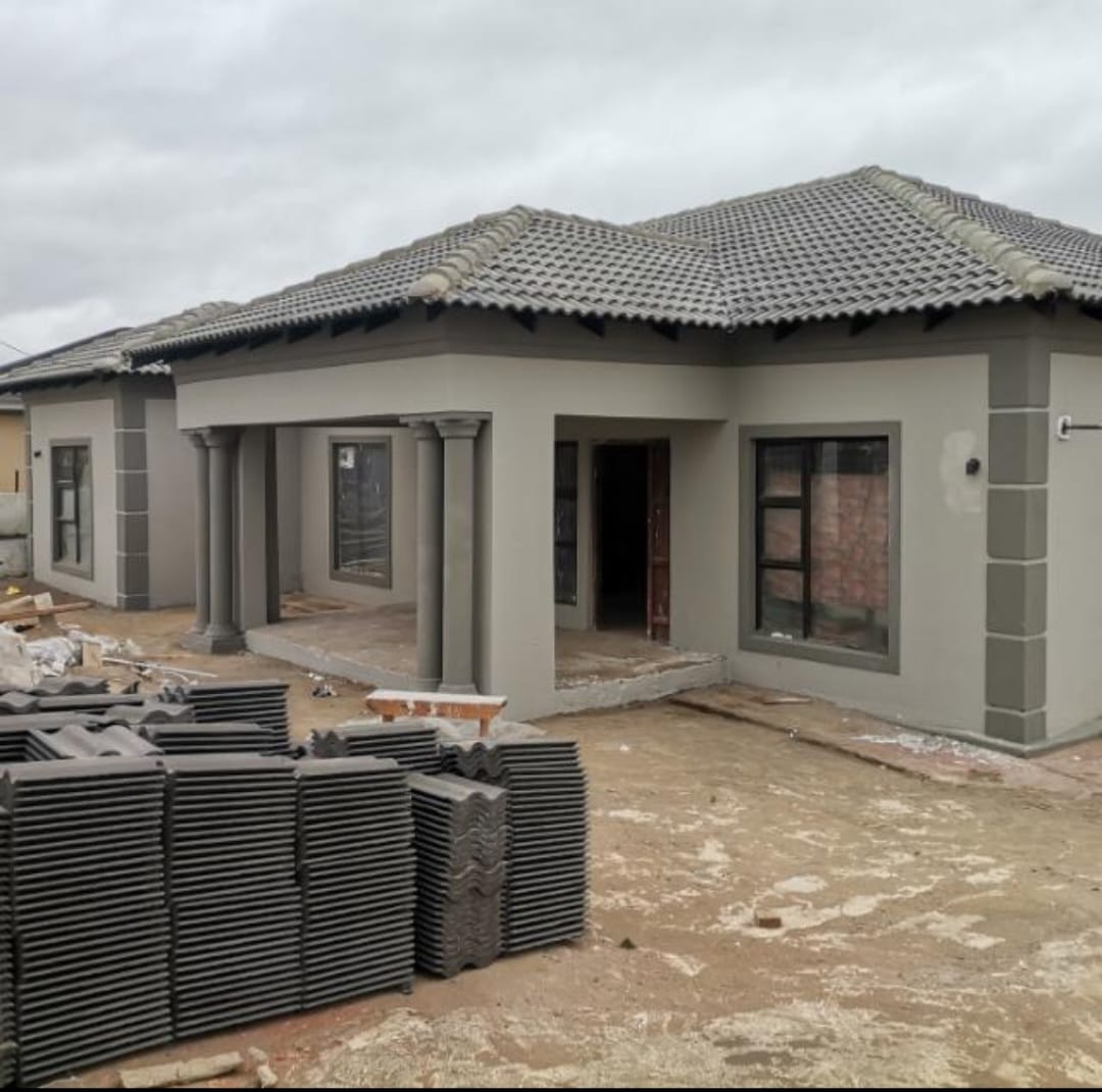 Grey house nearing completion with roof tiles stacked